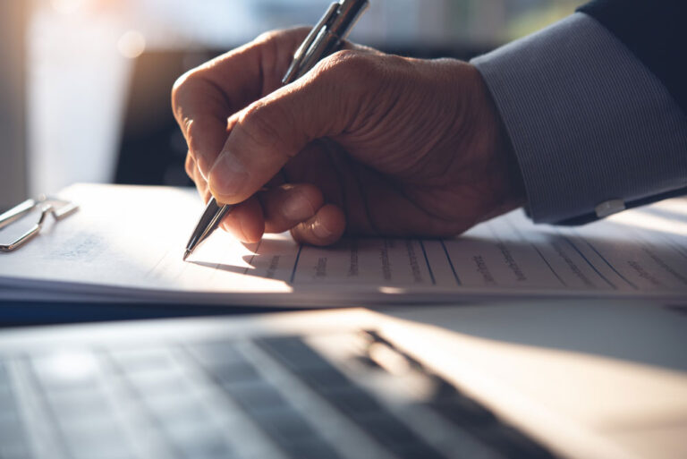 Close up of male hand writing with a pen to fill out a form