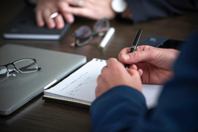 Close up of male hands holding a pen over a pad of paper