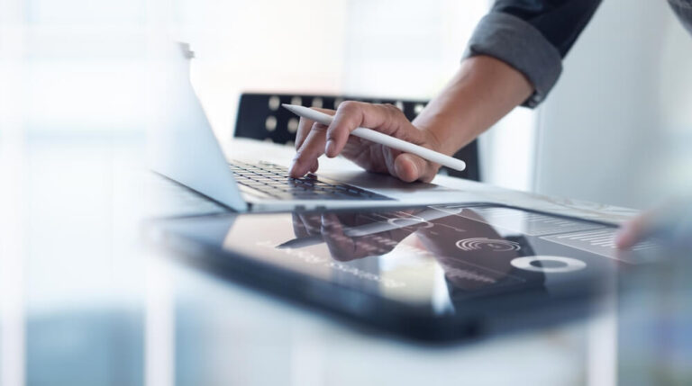 Person working at laptop and tablet at the same time