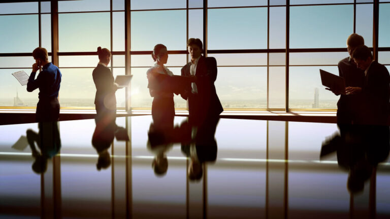 A large high rise conference room with six colleagues regarding documents together