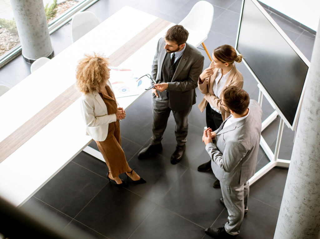 Overhead shot of four colleagues standing in semi circle in an office setting